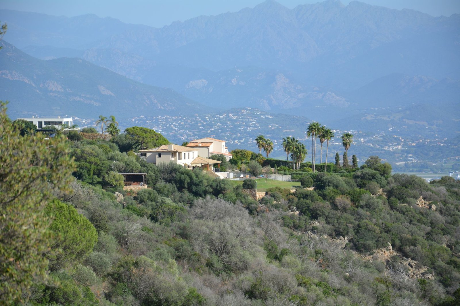 Rue calme de Corte en Corse avec maisons en pierre et montagnes en arrière-plan