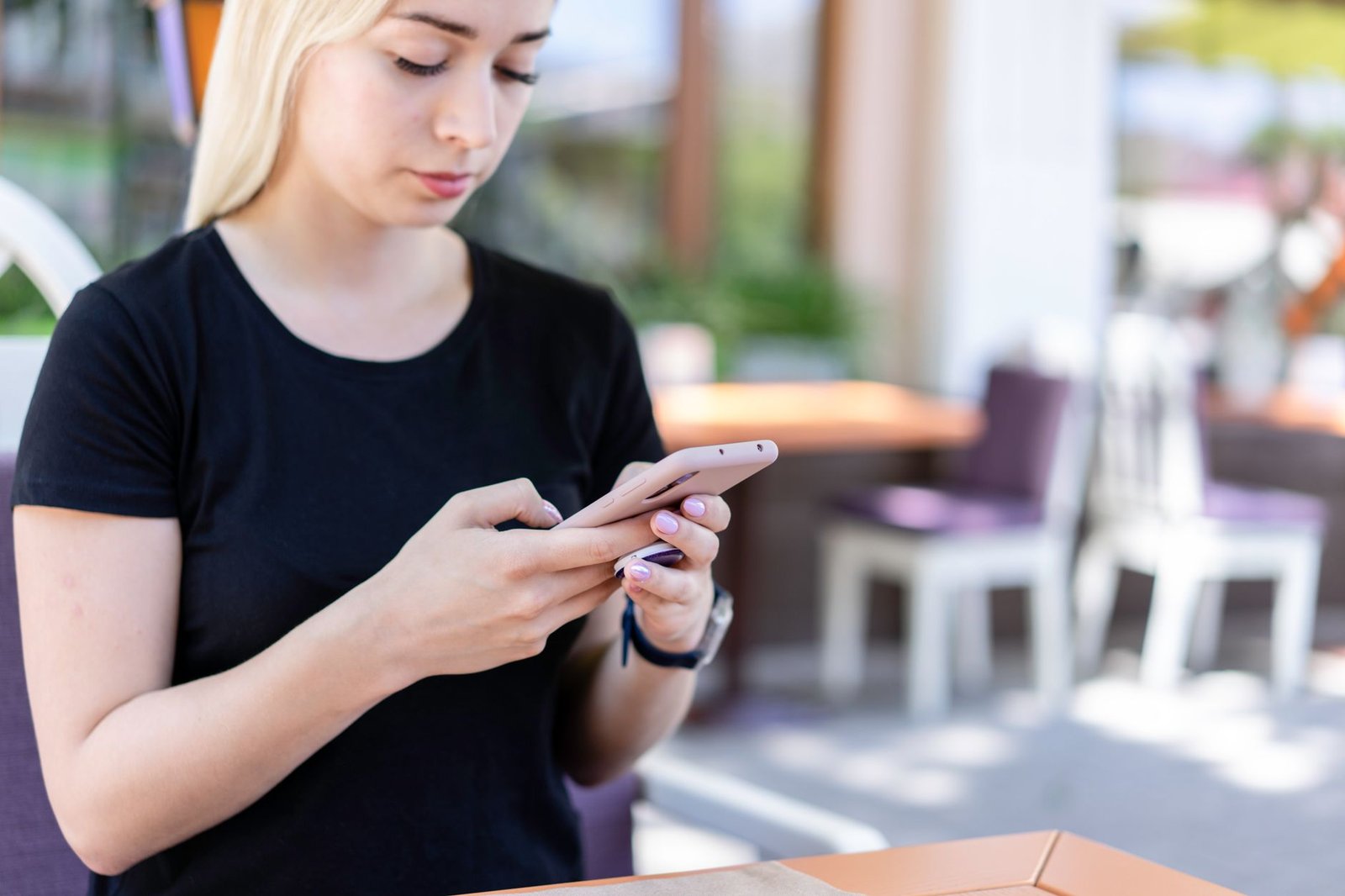 Personne rédigeant un message courtois sur son téléphone à une terrasse de café