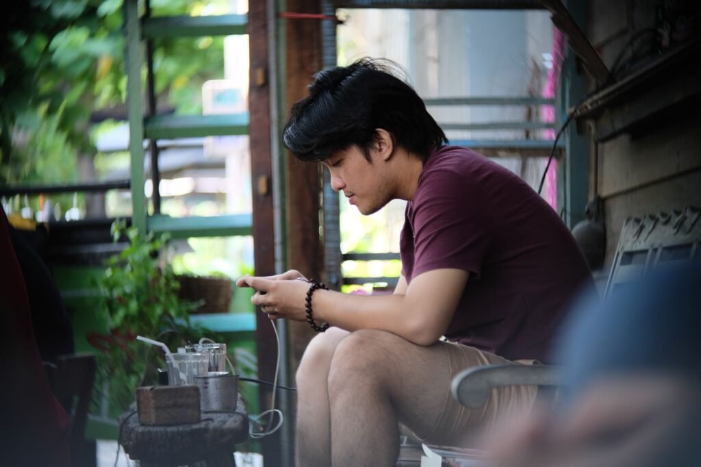 Homme consultant son téléphone dans un café, illustrant la préparation d'un premier message.