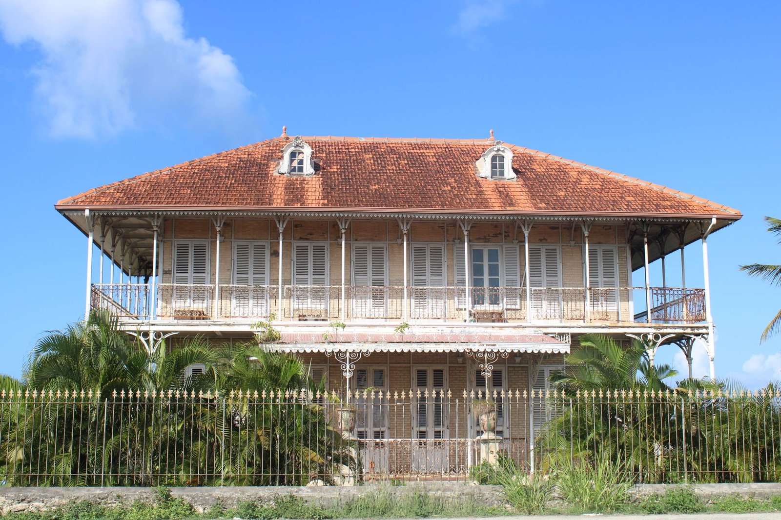 Rue calme de Les Abymes en Guadeloupe au coucher du soleil, maisons créoles et palmiers