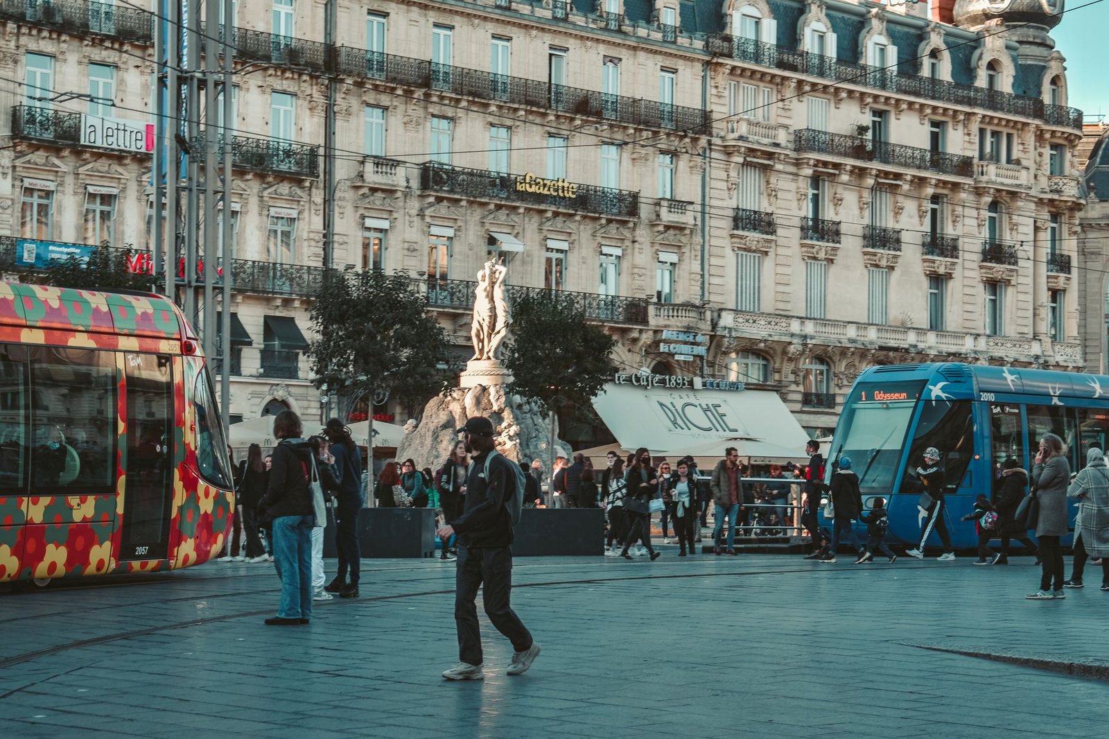 Place animée de Montpellier au crépuscule, cadre discret pour une rencontre