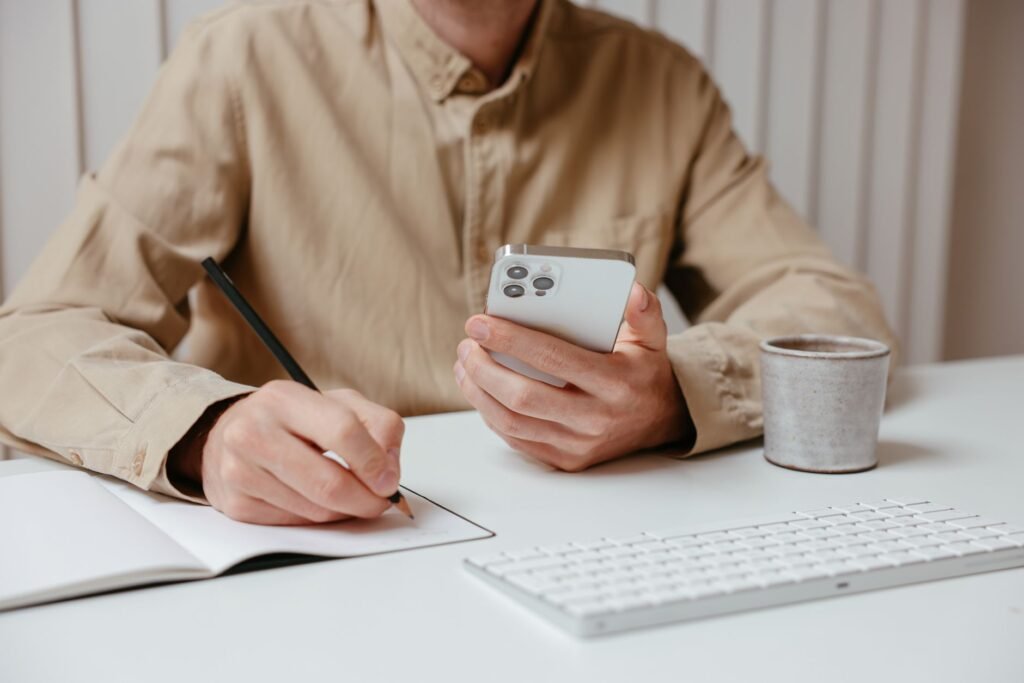 Carnet, stylo et smartphone sur une table, symbolisant la préparation d'un premier contact