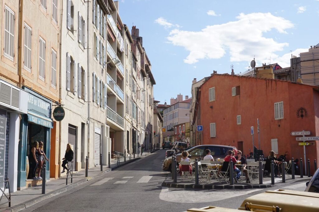 Rue résidentielle calme de Marseille en fin d'après-midi, façades en pierre et volets verts