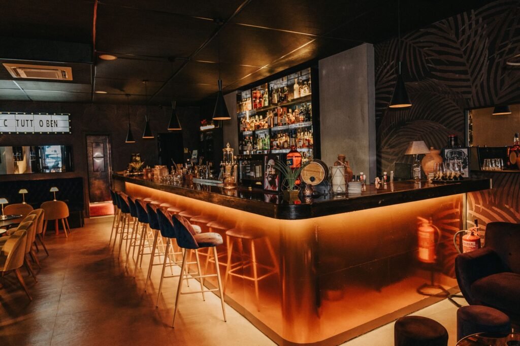 Intérieur d'un bar discret en Guyane avec éclairage tamisé et plantes tropicales, ambiance nocturne sobre.