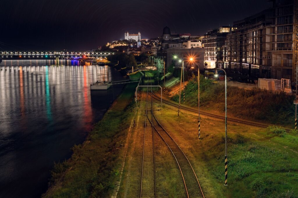 Chemin de promenade au bord de l'Oise la nuit avec reflets et lumières urbaines