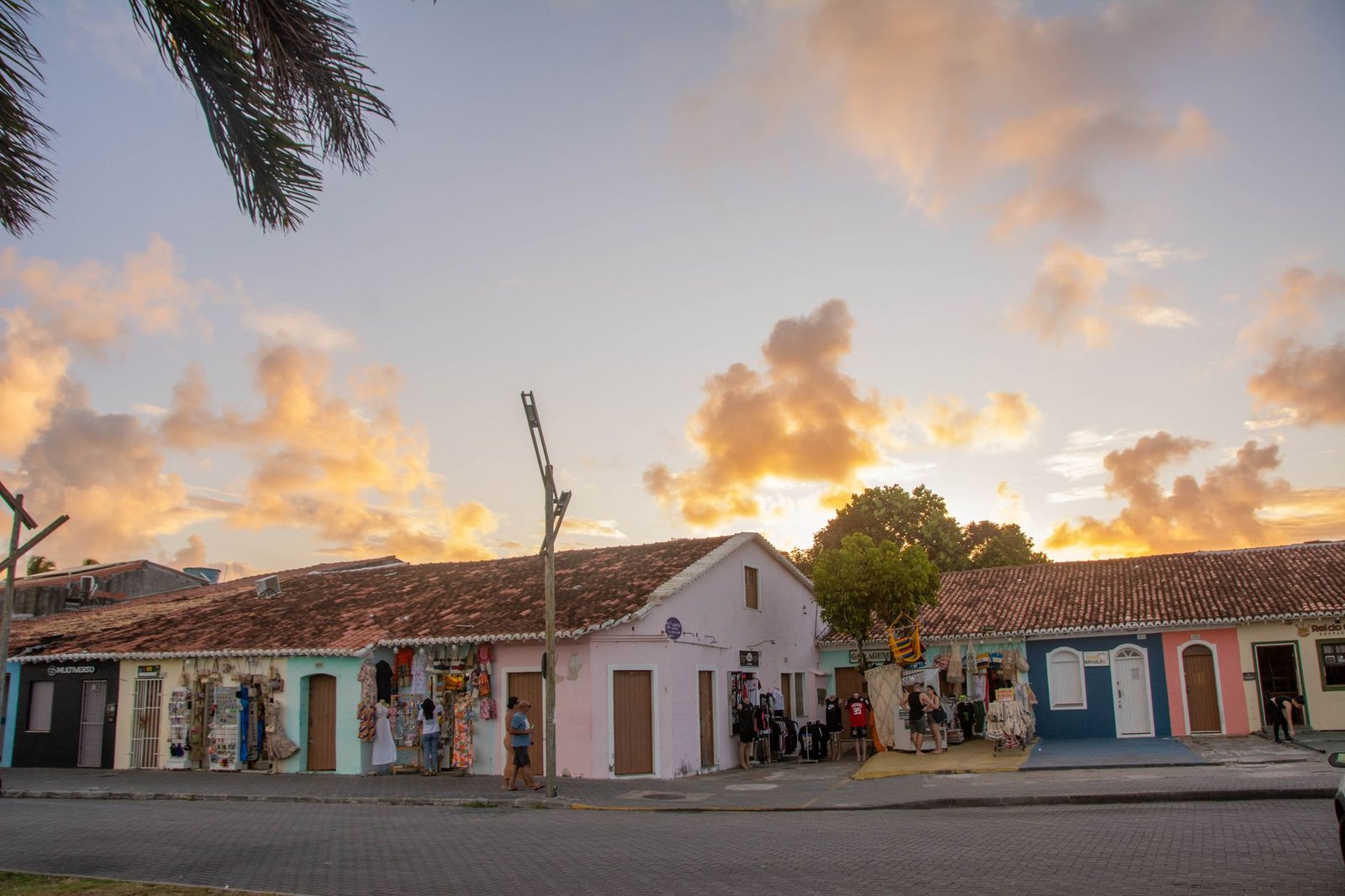 Rue calme d'une ville tropicale française au crépuscule, lumières chaudes et commerces qui ferment